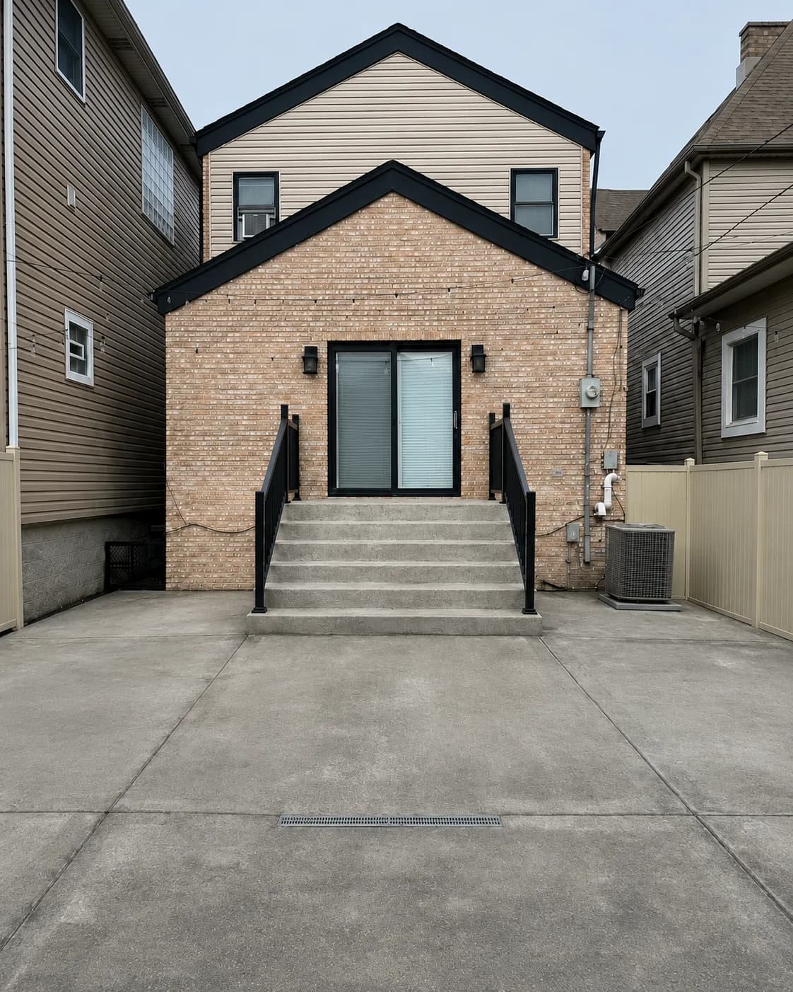 Bare gray concrete back patio and steps before coating, behind a brick home