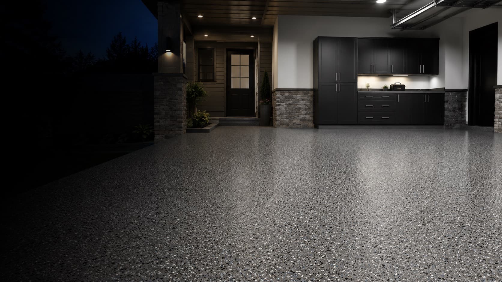 Grey full-flake garage floor coating by Revived Concrete Coatings, lit at dusk beside black cabinets