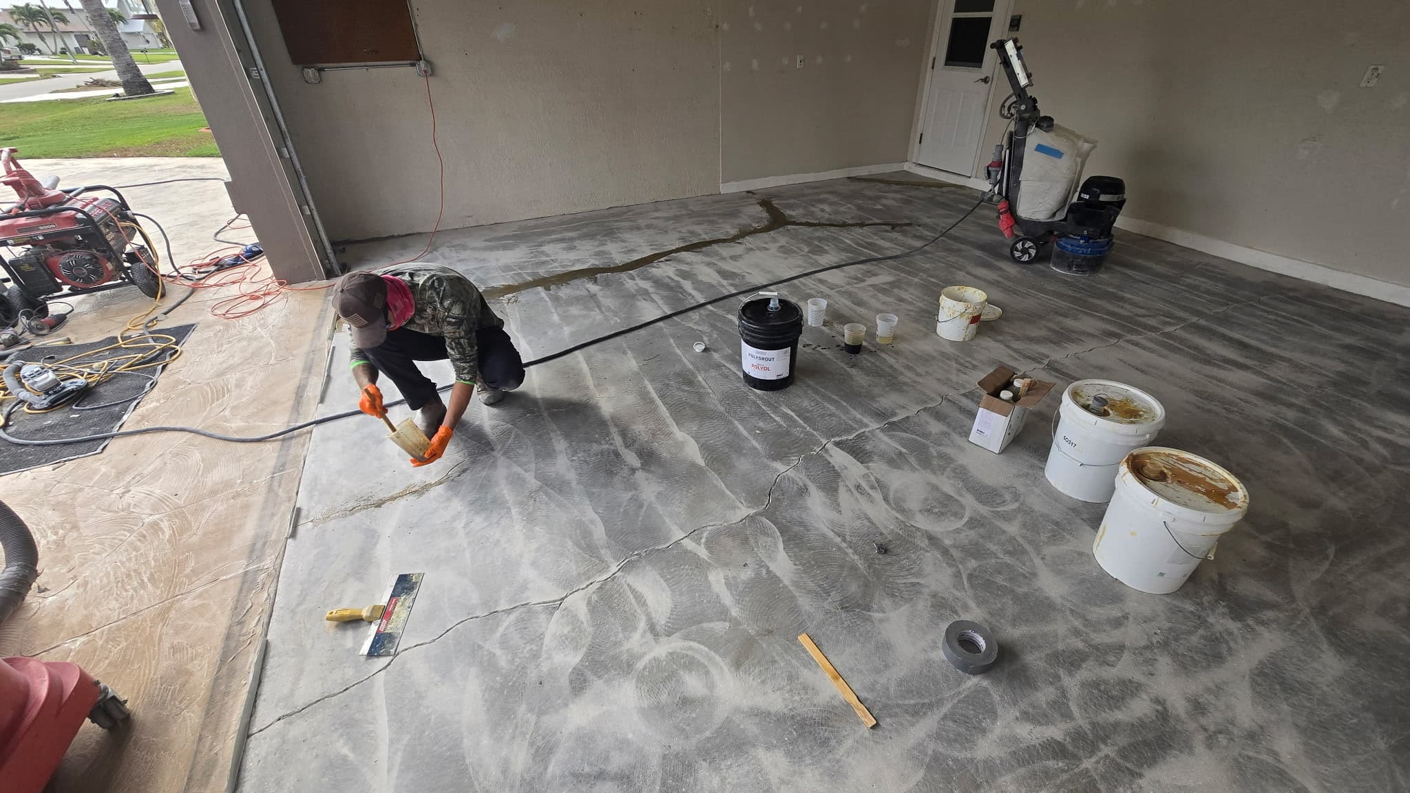 Technician troweling polyurea repair compound into a crack on a freshly diamond-ground garage slab