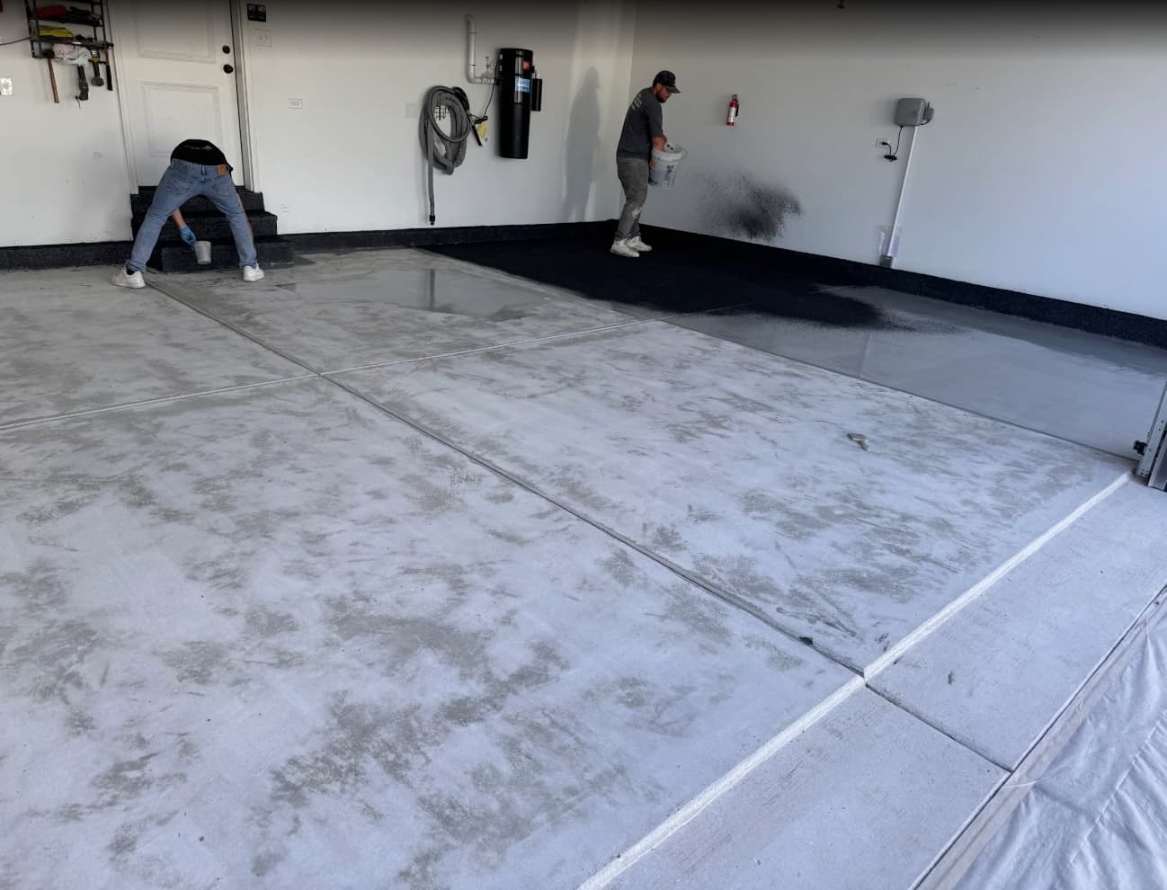 Two installers hand-broadcasting decorative flake across a garage floor while the base coat is still wet