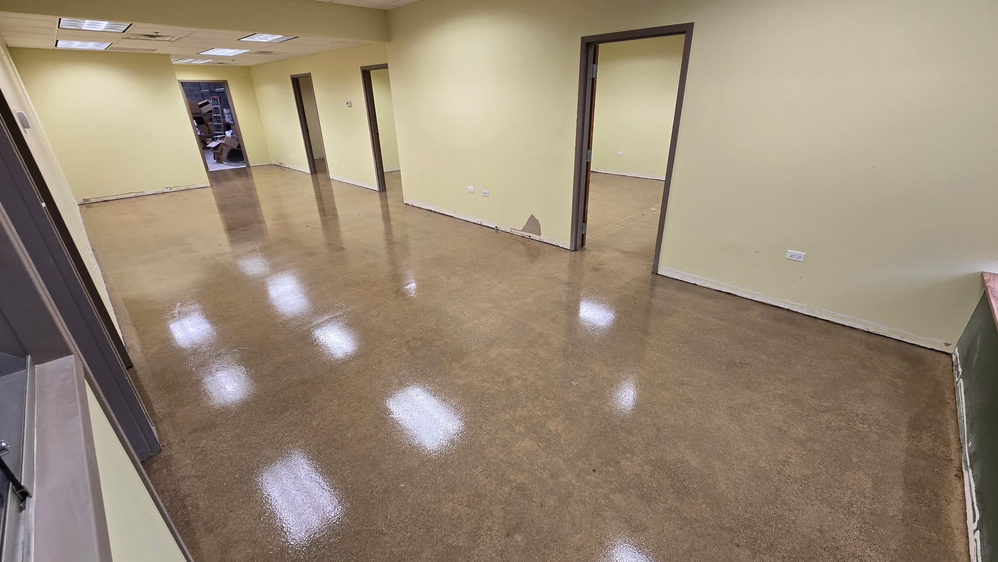 Diamond-ground concrete floor sealed to a high gloss under a clear polyaspartic topcoat, ceiling lights mirrored in the surface