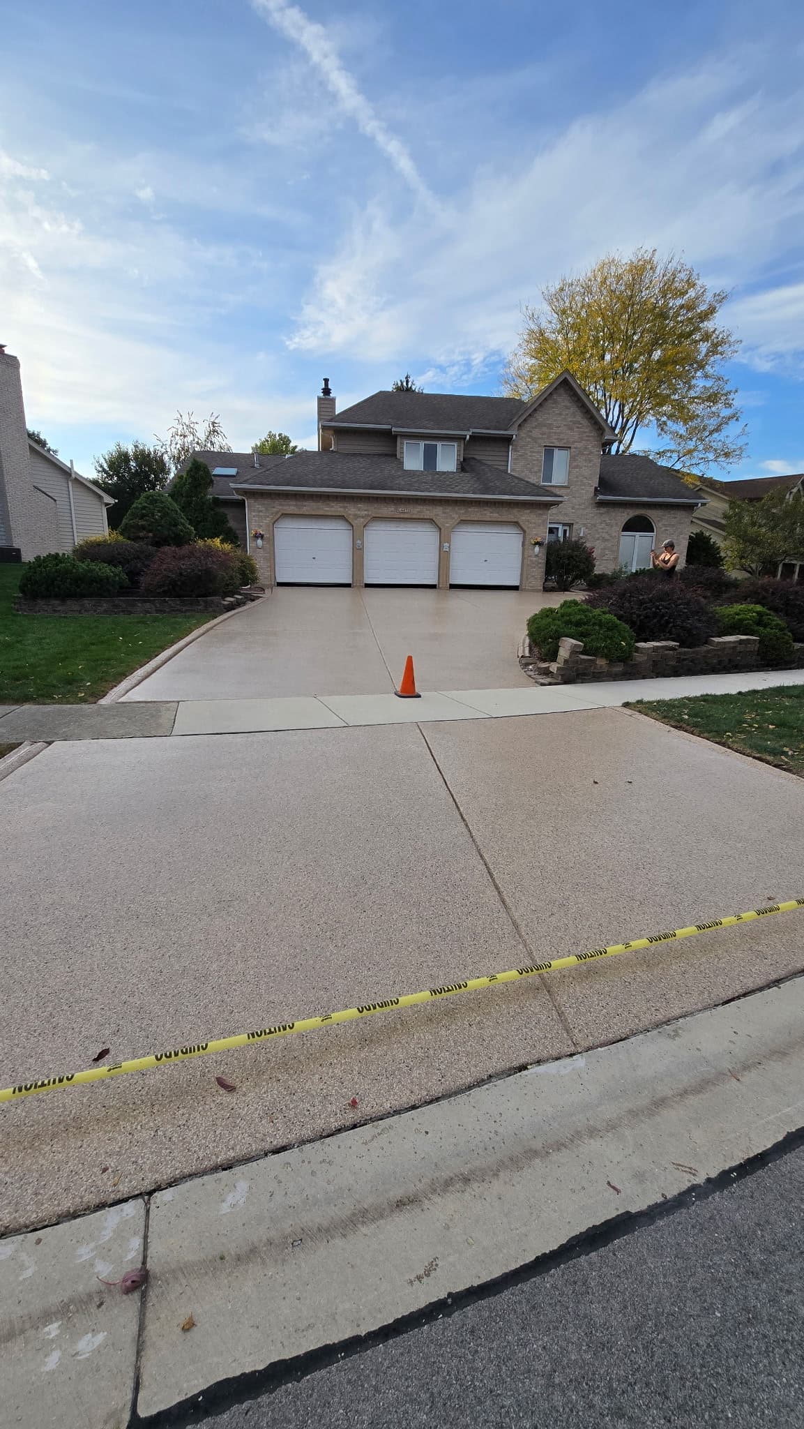 Finished driveway and apron coating taped off to cure outside a three-car garage